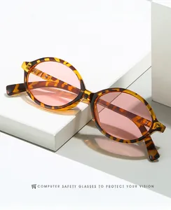 Détail de lunettes de soleil ovales rétro écaillées avec verres roses sur socle blanc