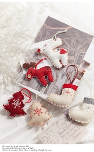 Detail of handmade wool felt Christmas ornaments with reindeer and tree shapes on vintage paper
