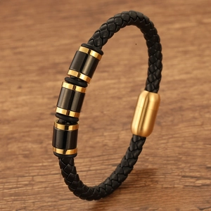 Close-up of black braided leather men's bracelet with gold magnetic clasp and metal beads