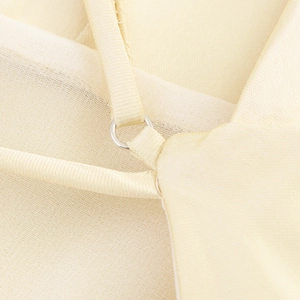 Detailed close-up of champagne satin fabric with mesh stitching and silver metal ring