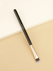 Detailed close-up of tongue-shaped concealer brush with dual-tone soft fiber bristles