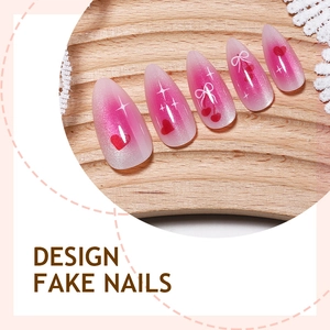 Pink cat-eye fake nails with bow and heart designs on a minimalist wood tray