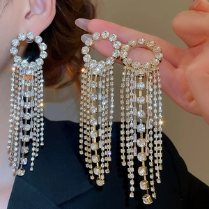 Detail view of sparkling rhinestone tassel earrings with golden geometric round studs