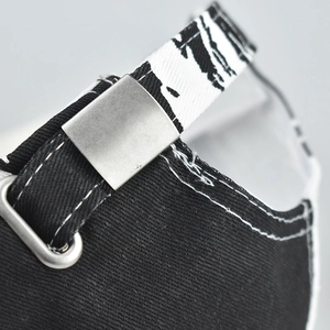 Macro detail of adjustable metal buckle and tie-dye strap on black cotton baseball cap