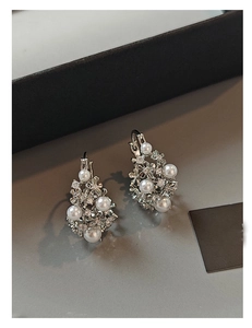 Detailed macro view of silver hollow floral basket earrings with pearls and crystals