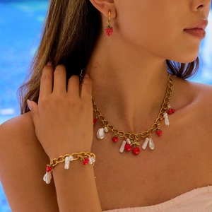 Golden titanium steel jewelry set with red strawberries and pearls on a female model
