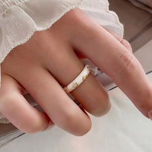 Dettaglio di un anello in smalto bianco con fiori in rilievo dorati e stile sobrio