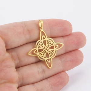 Golden Celtic witch knot pendant with hollow cutout design shown in hand over white background