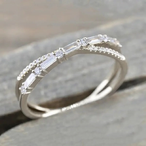 Macro shot of a silver crisscross ring featuring inlaid round and baguette cut crystals