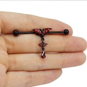 Macro shot of gothic industrial barbell with red bat design and teardrop pendant