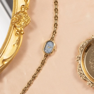 Retro gold quartz watch with oval grey dial on a vintage mirror and golden tray