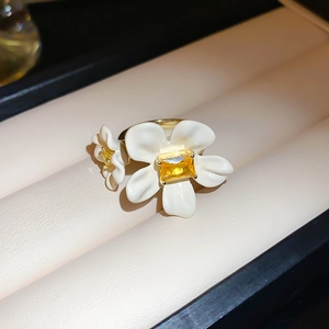 Detailed macro view of gold-plated double floral ring with yellow gem on ivory leather