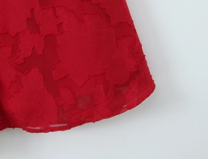 Vue détaillée du tissu jacquard à motif rose rouge sur une robe de soirée élégante