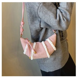 Dettaglio borsa croissant in camoscio rosa con strisce in shearling su maglione grigio