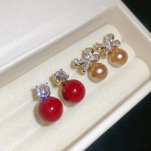 Detail of red pearl and champagne bow earrings displayed in a luxury velvet jewelry box