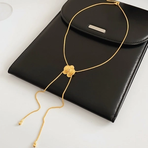 Dettaglio della collana con ciondolo a fiore dorato e texture in metallo spazzolato