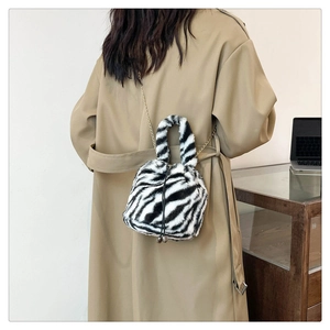 Detail of zebra pattern faux fur bucket bag with metal chain strap on model