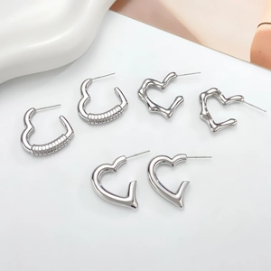 Detailed view of three silver heart-shaped hoop earrings with different textures