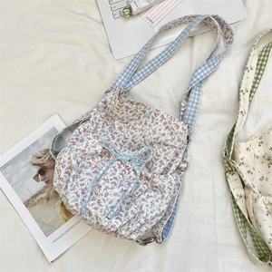 Detail of floral canvas backpack featuring blue plaid bow ties and drawstring closure