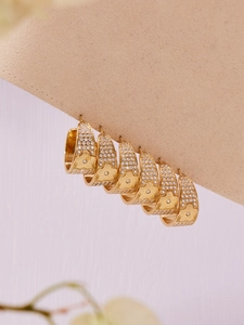 Macro detail of gold hoop earrings with micro-pave zircon stones and floral relief pattern