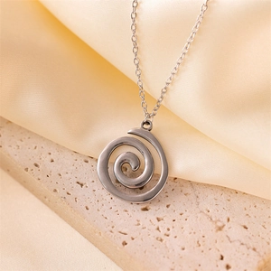 Close-up of silver spiral pendant on stone base with soft beige satin fabric background