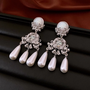 Vintage silver earrings with opal stone and pearl drop pendants on red silk background