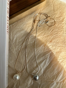 Macro shot of minimalist gold and silver snake chains with white and grey pearl pendants