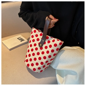 Detailed view of red polka dot canvas bucket bag with brown leather handles and interior