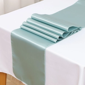 Detailed view of light blue satin table runner showcasing smooth glossy texture and drape
