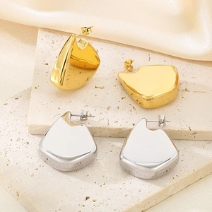 Close-up of chunky irregular gold and silver fin earrings on a travertine stone plate