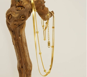 Detailansicht der goldene doppellagigen Edelstahl-Perlenkette an einem Holzzweig