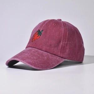 Dettaglio del ricamo a fragola sul cappello in cotone lavato color bordeaux scuro