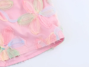 Macro detail of pink mesh blouse featuring 3D floral embroidery and sparkling sequins