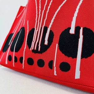 Close-up of thick red knitted fabric with black polka dots and white geometric lines