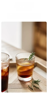 Close-up of vertical striped glass cups with ice and rosemary on a wooden tray