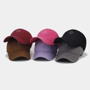 Detail of six colorful cotton baseball caps with minimalist sun embroidery on front