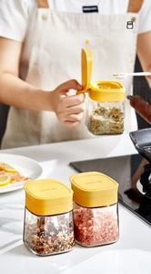 Close-up of glass spice jars with yellow lids in a warm kitchen setting with soft lighting