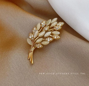 Macro shot of golden wheat brooch with opal stones and crystals on fabric