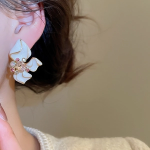 Detailed close-up of a white enamel flower earring with gold edges and pink rhinestones