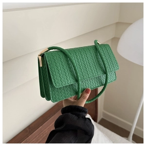 Close-up of green woven leather shoulder bag with gold metal buckle and flap design