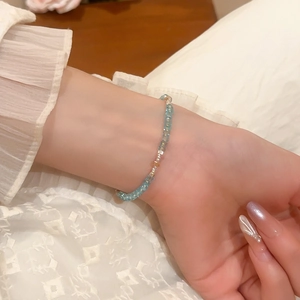 Close-up of light blue crystal beaded bracelet with gold accents on a wrist
