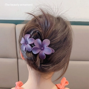 Detail view of large purple flower hair claw clip on a low bun hairstyle