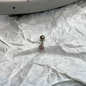 Macro shot of silver stainless steel stud earring with a claw-set pink heart zircon stone