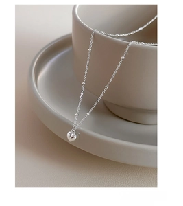 Detail of S925 sterling silver heart necklace hanging on a ceramic cup edge