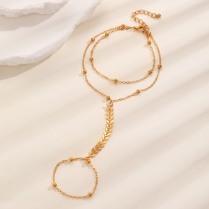 Detail of gold hand chain with layered pearl beads and arrow geometric accent