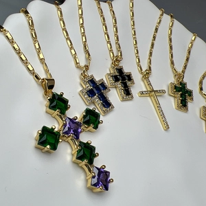 Gold cross necklaces with square colored zircon pendants on a white display stand