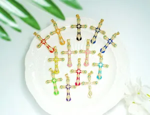 Macro shot of colorful enamel cross pendants with 18K gold plating on a white ceramic tray