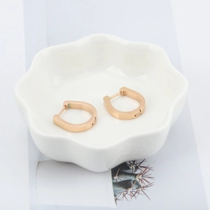 Pendientes minimalistas de acero inoxidable en forma de U de oro rosa en bandeja de cerámica