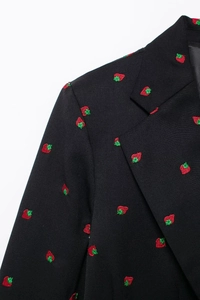 Gros plan de la broderie de fraises sur le revers et l'épaule du blazer noir