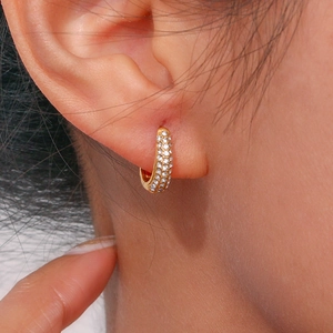 Macro shot of gold-plated U-shaped earrings with micro-pave white zircon stones on ear
